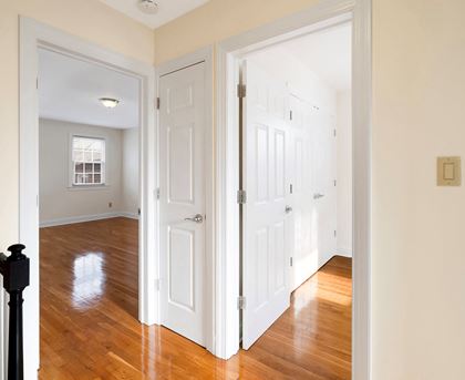 a bedroom with two closets and a hallway with wood floors
